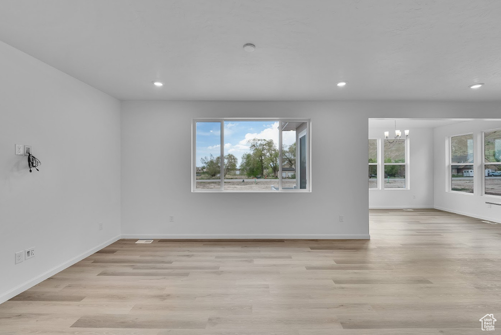 Spare room with a chandelier, recessed lighting, light wood-type flooring, and baseboards
