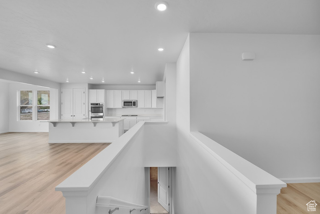 Staircase with recessed lighting, wood finished floors, and baseboards