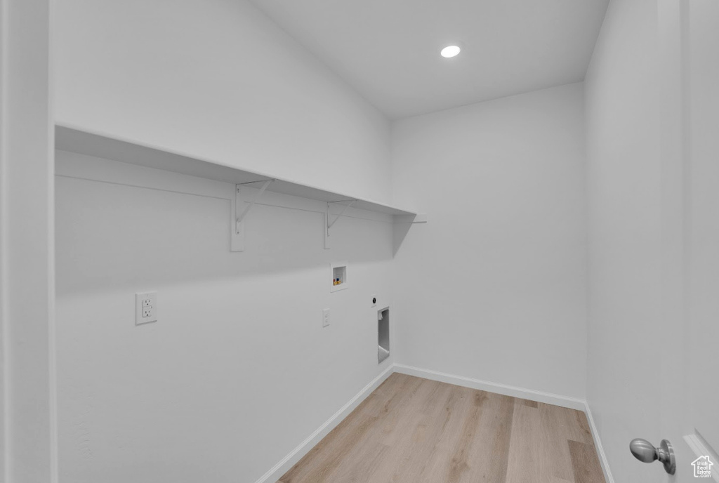 Clothes washing area featuring washer hookup, light wood-style floors, baseboards, hookup for an electric dryer, and gas dryer hookup