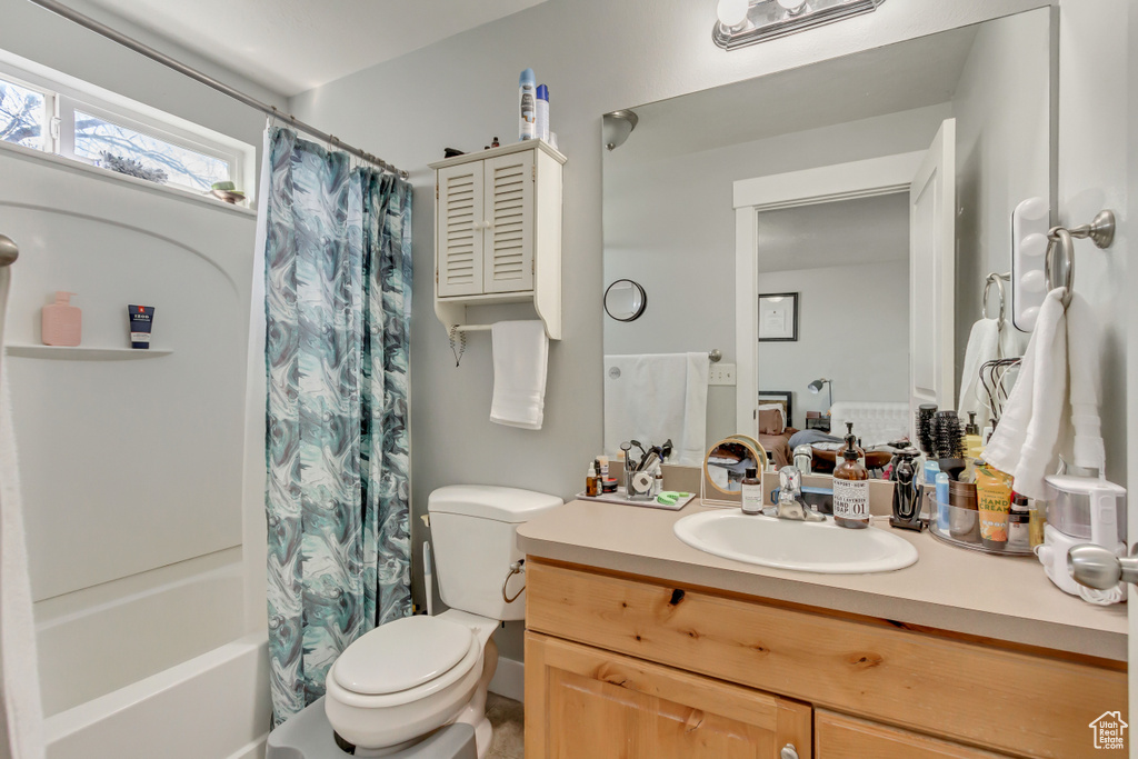Full bath featuring toilet, vanity, and shower / bath combo with shower curtain