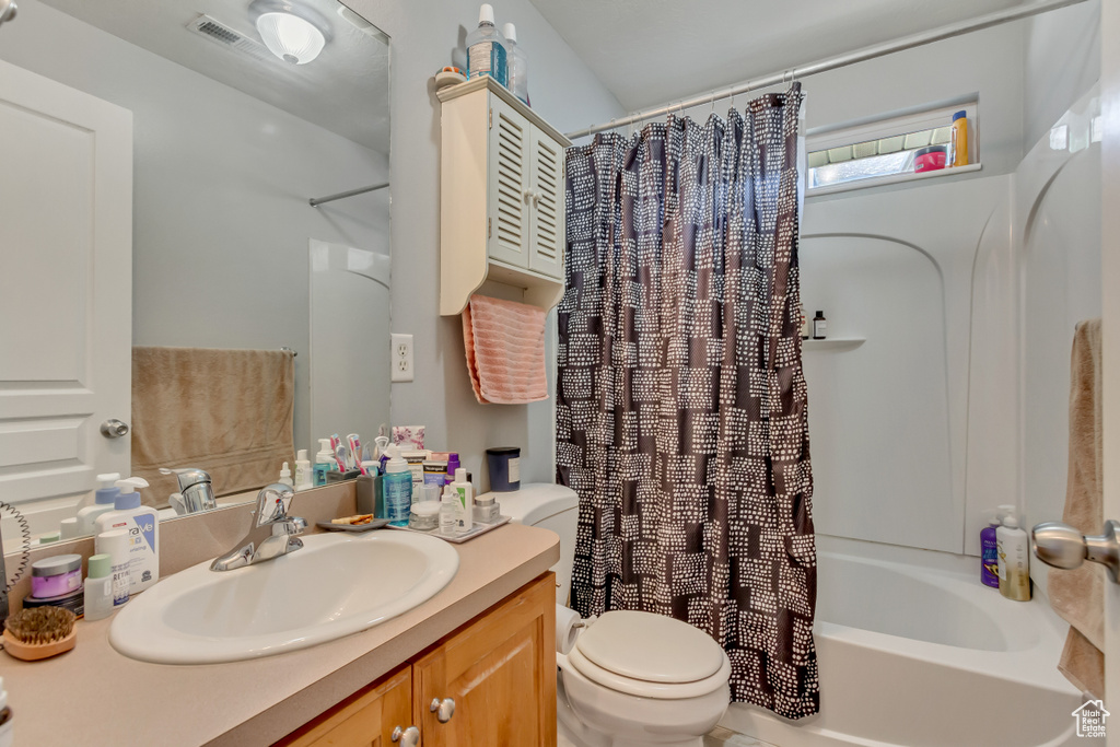 Full bathroom with visible vents, toilet, vanity, and shower / bathtub combination with curtain