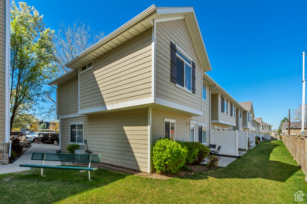 Rear view of house featuring fence, a yard, and a residential view
