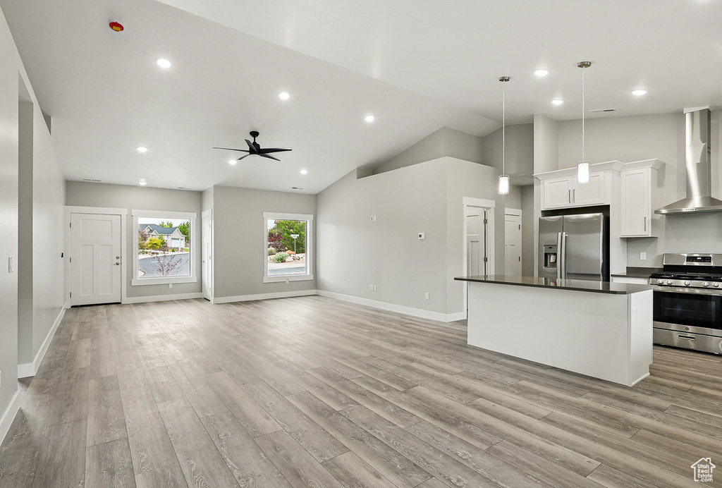 Unfurnished living room featuring light wood-type flooring, ceiling fan, baseboards, high vaulted ceiling, and recessed lighting