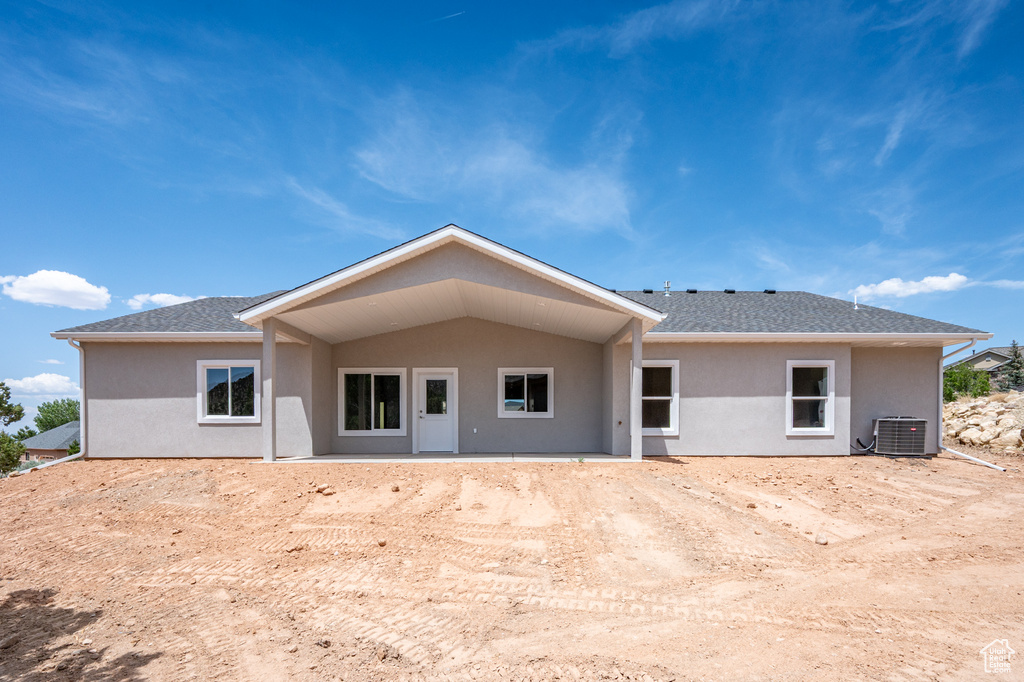 Rear view of property featuring stucco siding, central AC unit, and a shingled roof