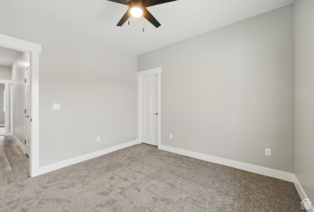 Carpeted empty room with a ceiling fan and baseboards