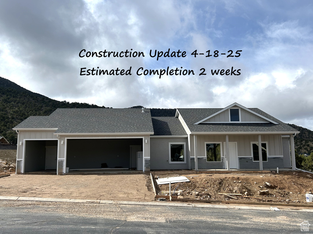 View of front of house with a shingled roof, board and batten siding, driveway, a mountain view, and a garage