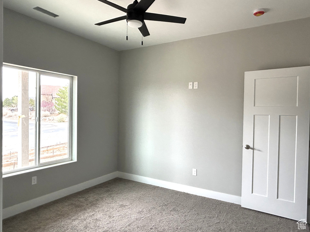 Carpeted spare room featuring visible vents, a ceiling fan, and baseboards