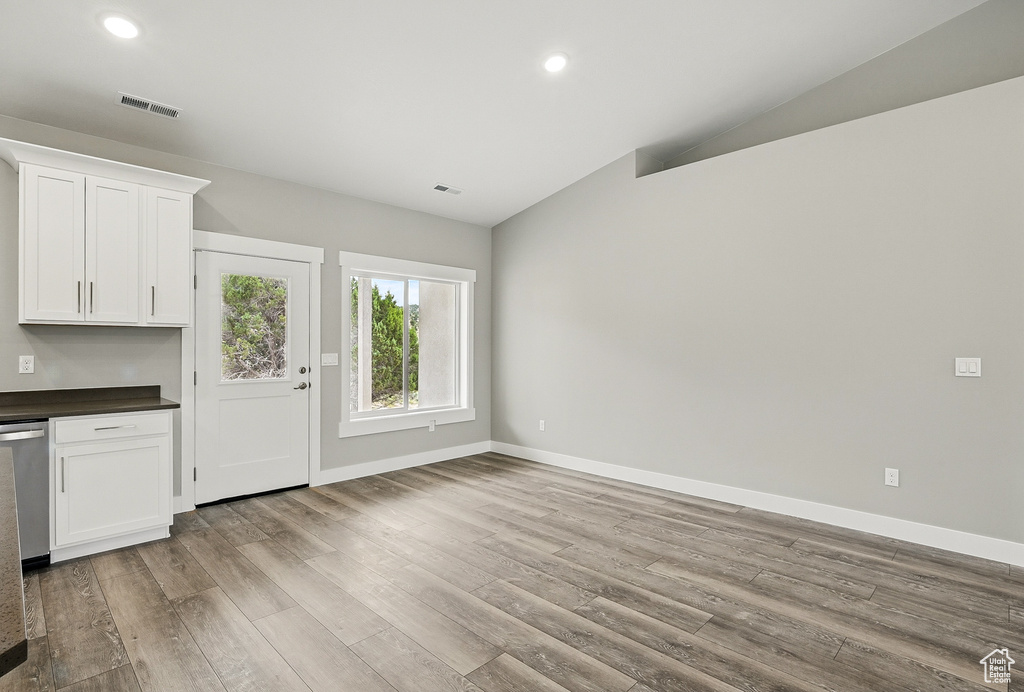 Unfurnished living room featuring lofted ceiling, wood finished floors, baseboards, and recessed lighting