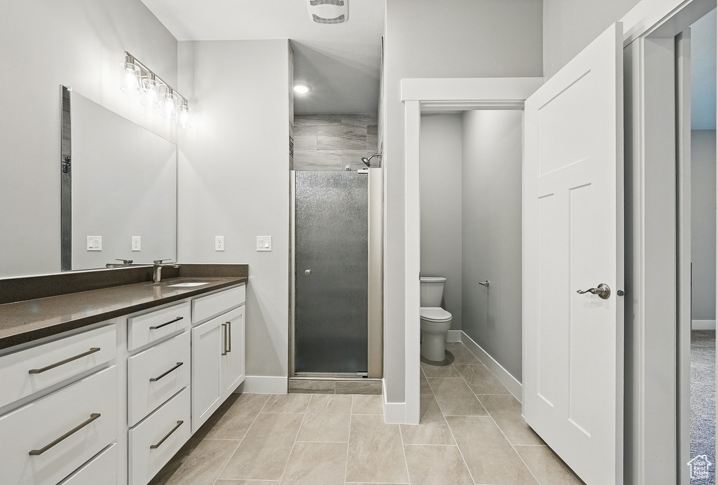 Bathroom with vanity, a shower stall, toilet, baseboards, and tile patterned floors