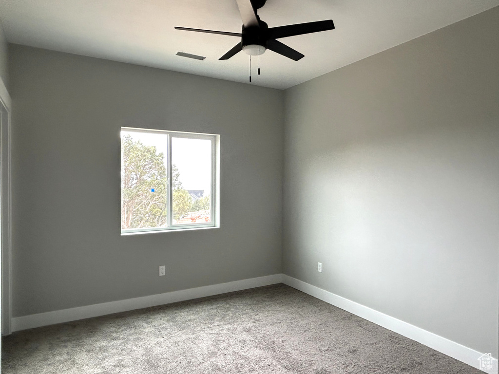 Carpeted spare room with visible vents, a ceiling fan, and baseboards