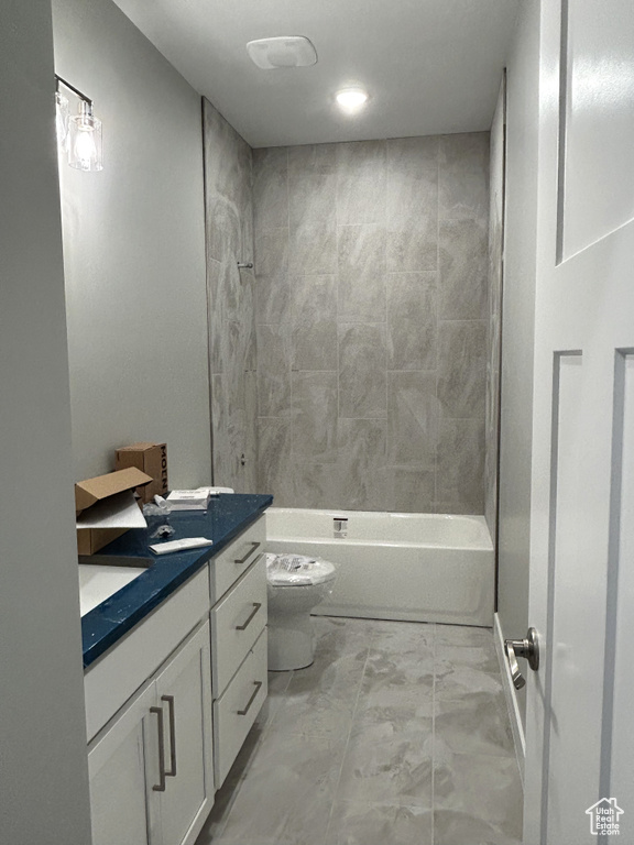 Bathroom featuring marble finish floor, toilet, vanity, and bathtub / shower combination