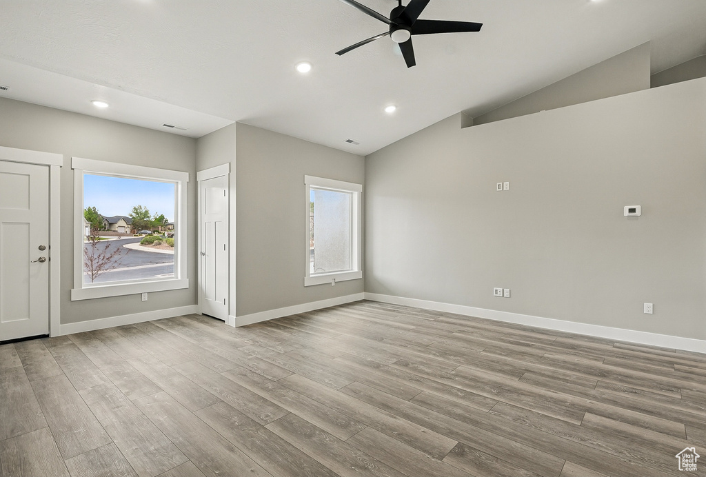 Unfurnished room featuring a ceiling fan, plenty of natural light, recessed lighting, wood finished floors, and lofted ceiling