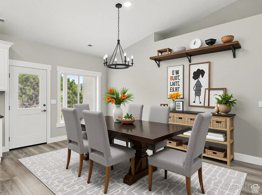 Dining area with vaulted ceiling, a chandelier, light wood finished floors, and baseboards