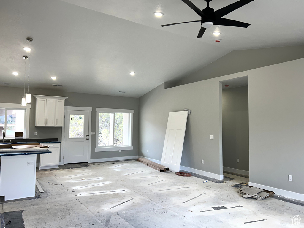 Unfurnished living room featuring ceiling fan, baseboards, and plenty of natural light