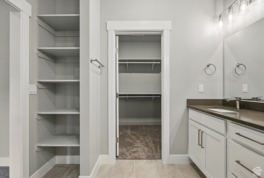 Bathroom with vanity, a walk in closet, and baseboards
