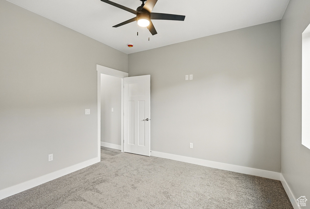 Spare room with light colored carpet, a ceiling fan, and baseboards