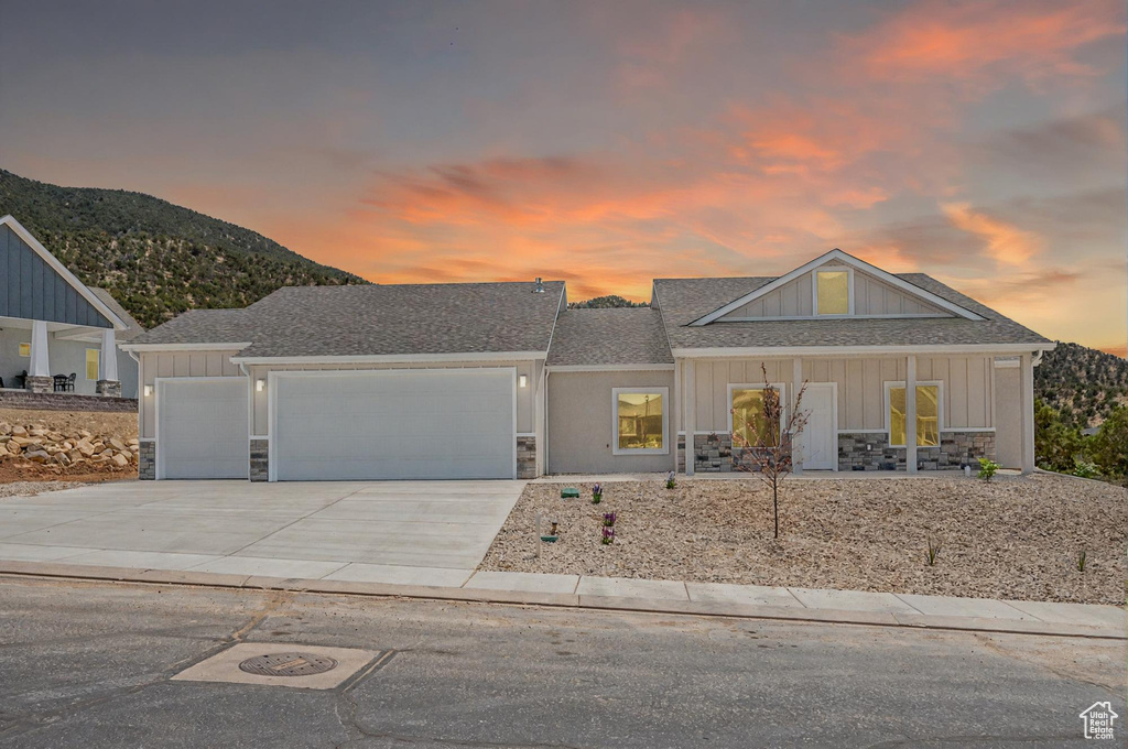View of front of home featuring stone siding, a garage, concrete driveway, a mountain view, and board and batten siding