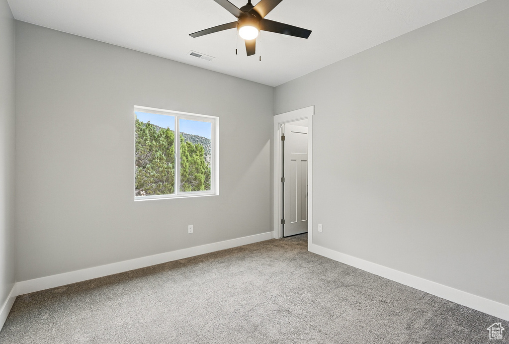 Carpeted spare room with baseboards and a ceiling fan