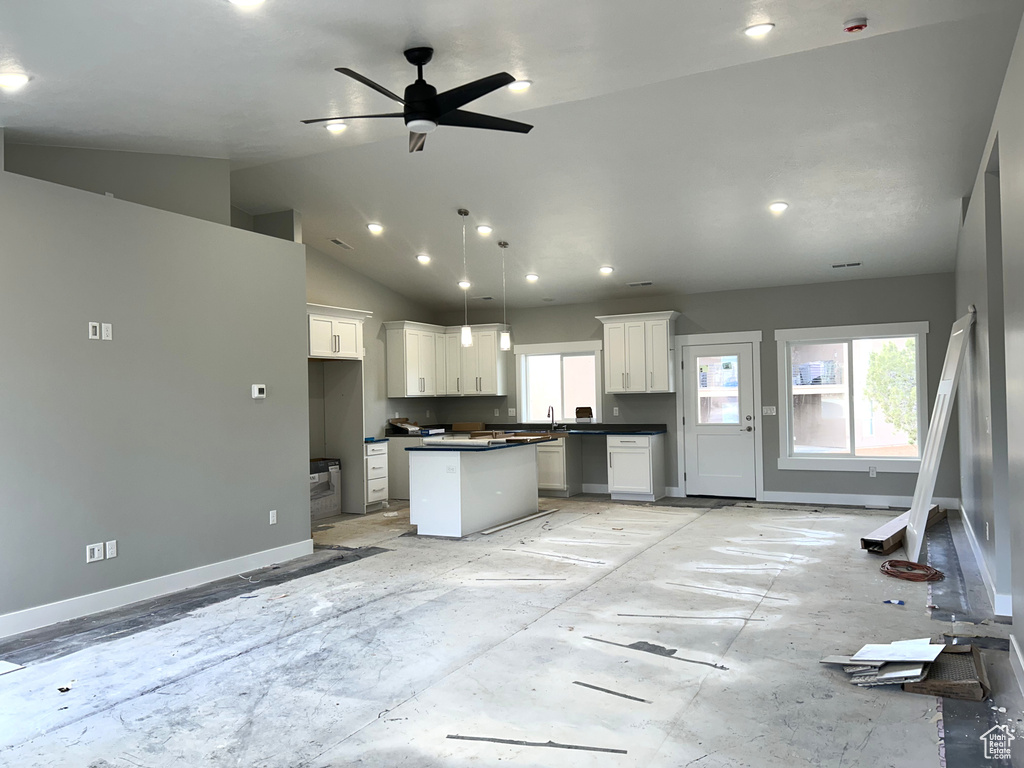Kitchen with ceiling fan, a wealth of natural light, dark countertops, and a kitchen island
