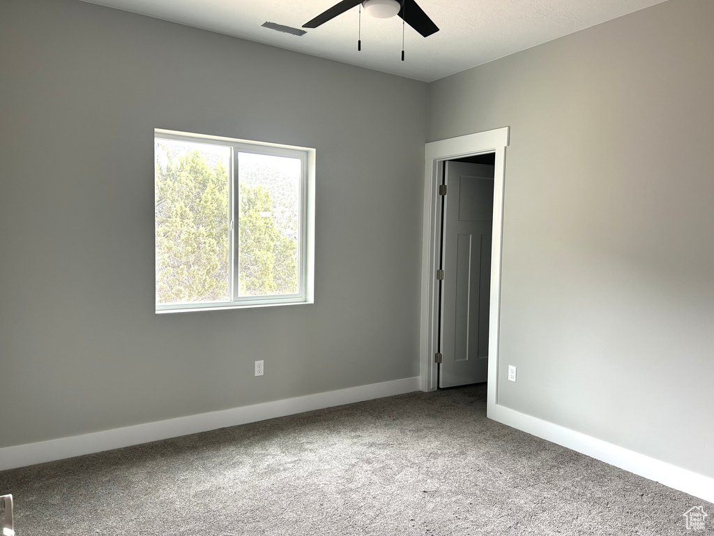 Carpeted empty room featuring baseboards and ceiling fan