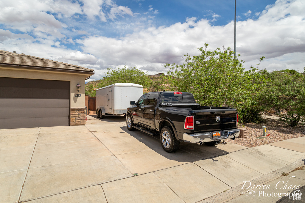 View of property exterior with stucco siding, a tile roof, driveway, and stone siding