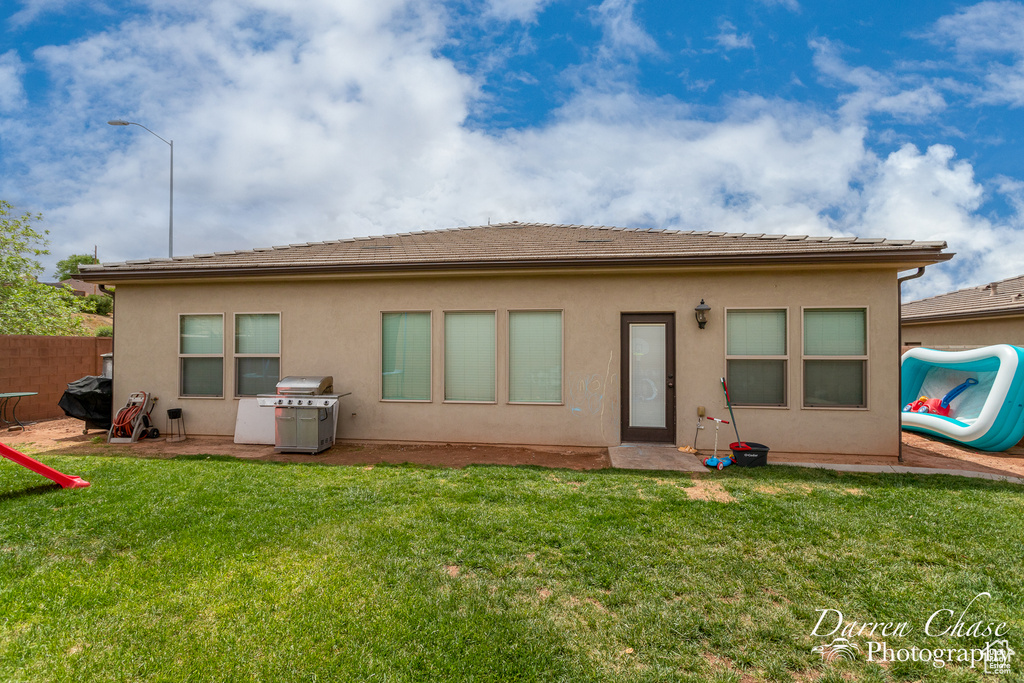 Back of house featuring a lawn, stucco siding, and fence