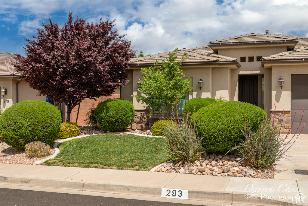 View of front of house featuring a tile roof, a front yard, and stucco siding