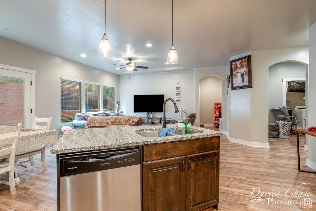 Kitchen with stainless steel dishwasher, a sink, arched walkways, open floor plan, and ceiling fan