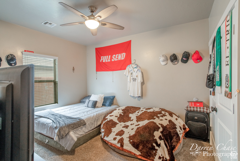 Carpeted bedroom featuring visible vents and a ceiling fan