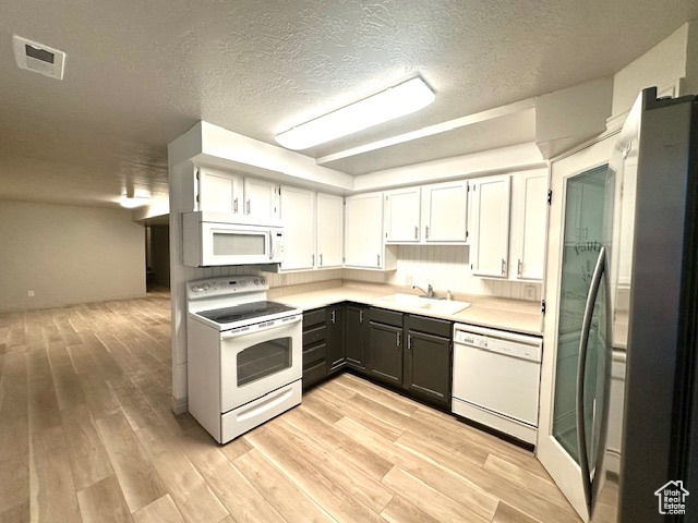 Kitchen with a sink, light wood-style floors, white appliances, light countertops, and visible vents
