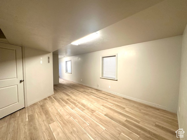 Basement with baseboards and light wood-style floors