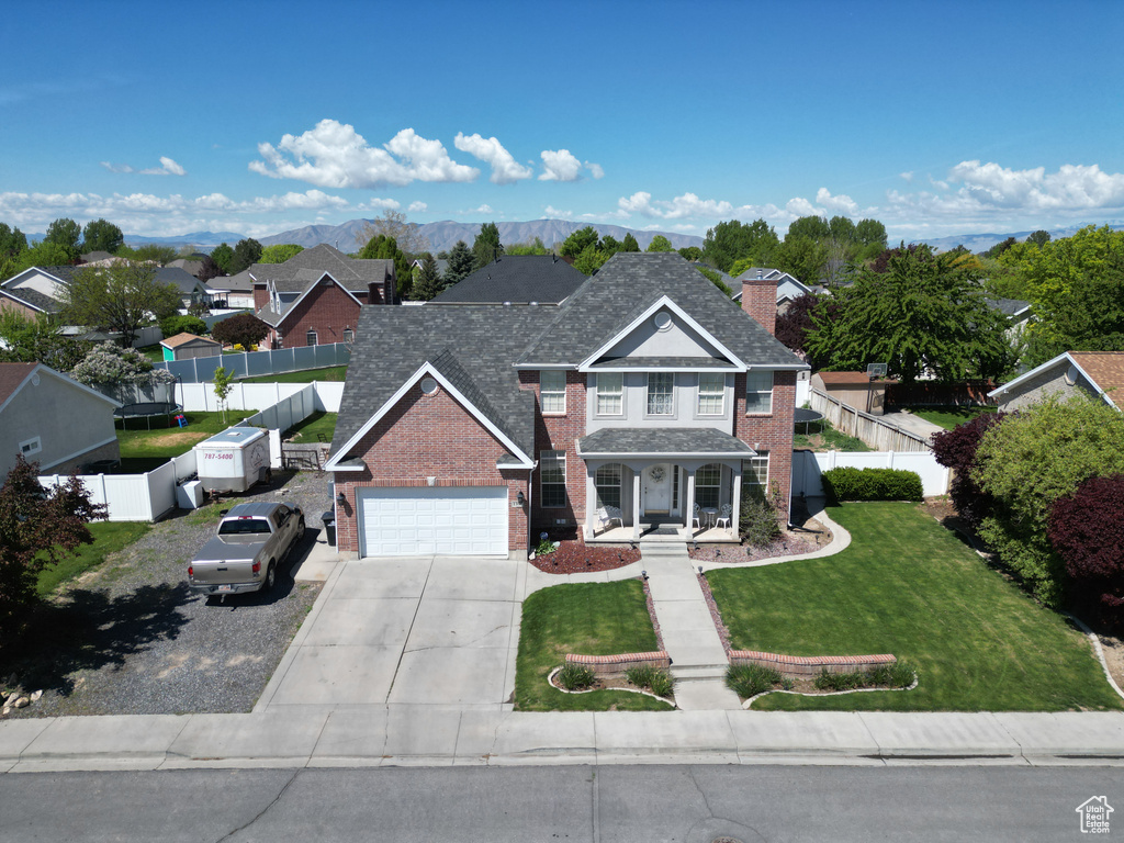 Traditional-style home with covered porch, brick siding, driveway, and fence