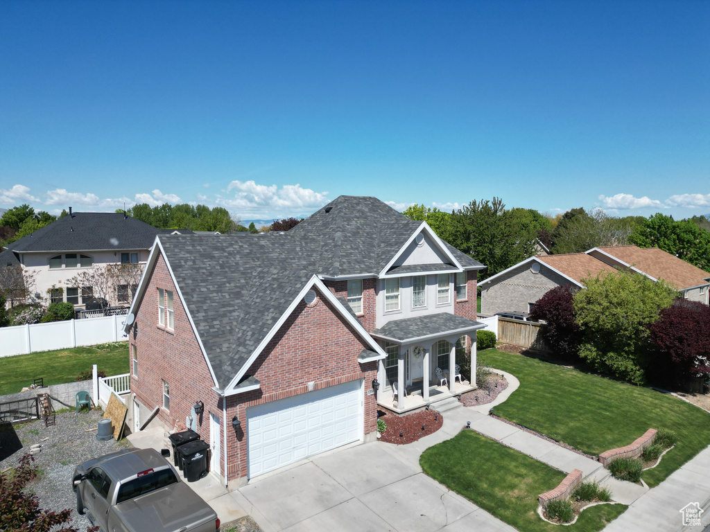 Traditional home with a garage, fence, a front lawn, brick siding, and driveway