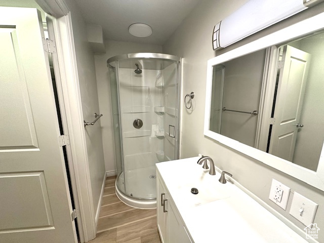 Bathroom featuring baseboards, a shower stall, vanity, and wood finished floors