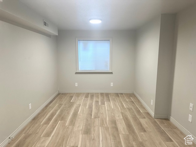 Empty room with visible vents, light wood-style flooring, and baseboards