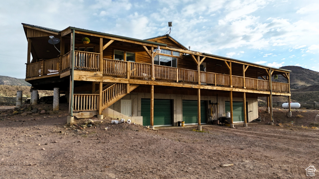 Back of property featuring driveway, a deck with mountain view, and a garage