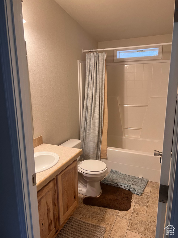Bathroom with toilet, shower / bath combo, vanity, and a textured wall