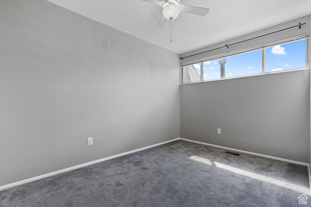 Carpeted spare room featuring visible vents, a ceiling fan, and baseboards