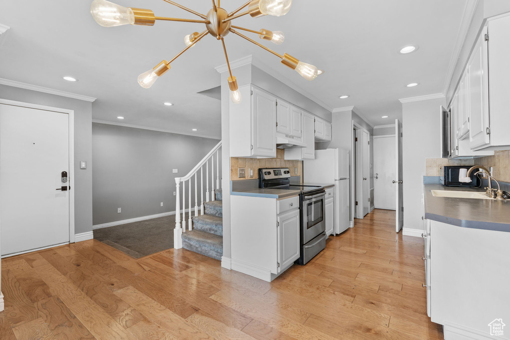Kitchen with a sink, stainless steel range with electric cooktop, backsplash, ornamental molding, and recessed lighting