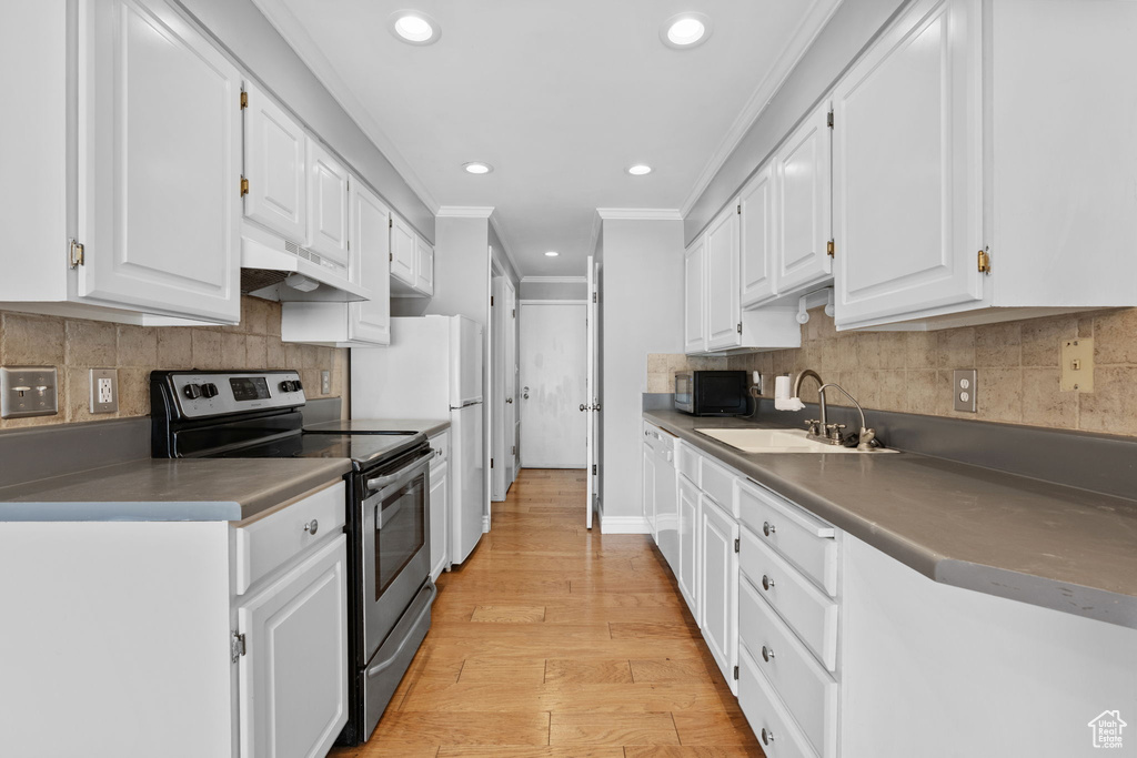 Kitchen featuring under cabinet range hood, a sink, white cabinetry, and stainless steel range with electric stovetop