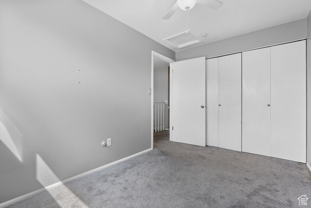 Unfurnished bedroom featuring attic access, ceiling fan, carpet flooring, and a closet
