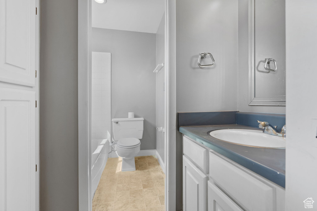 Bathroom with toilet, vanity, and baseboards