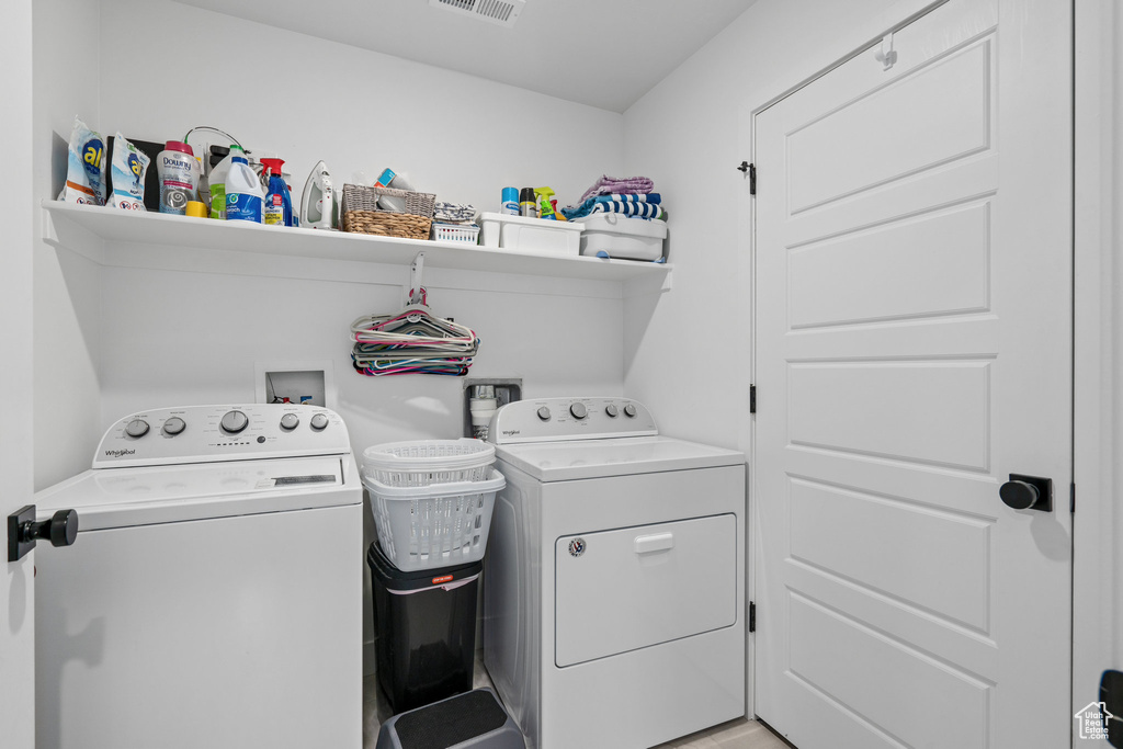 Washroom featuring washing machine and dryer, visible vents, and laundry area