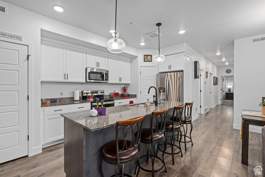 Kitchen featuring a kitchen breakfast bar, a sink, appliances with stainless steel finishes, visible vents, and recessed lighting