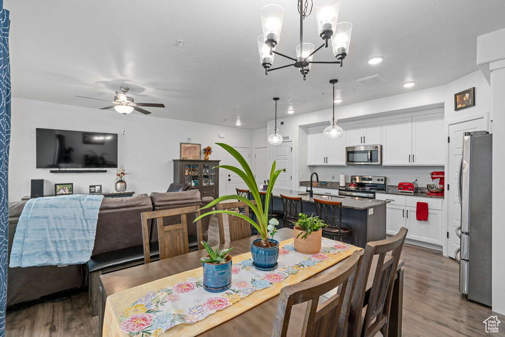 Dining area with ceiling fan with notable chandelier, recessed lighting, and dark wood-type flooring