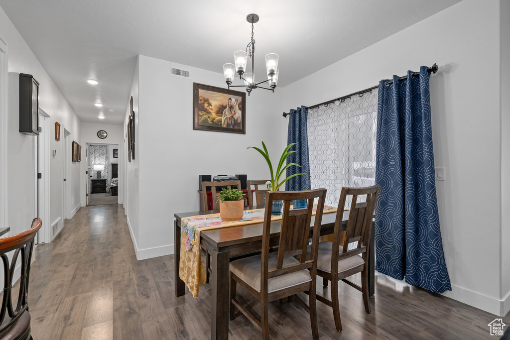Dining room with an inviting chandelier, wood finished floors, visible vents, and baseboards