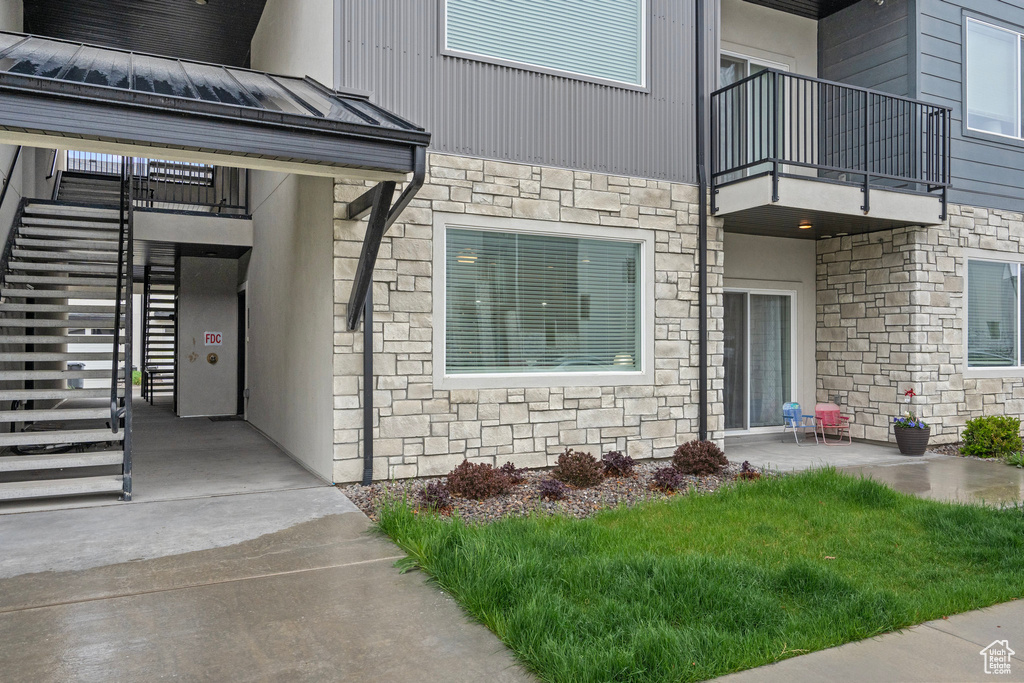 Entrance to property featuring metal roof, stone siding, a standing seam roof, and a balcony