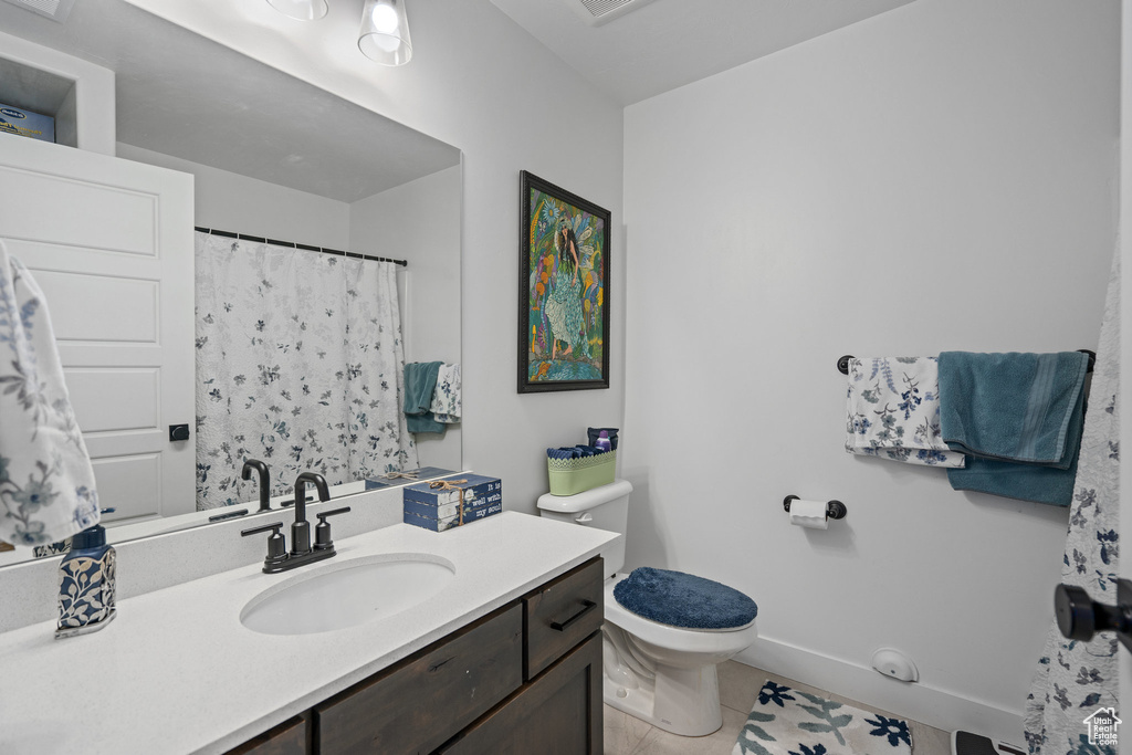 Full bathroom with toilet, vanity, and tile patterned floors