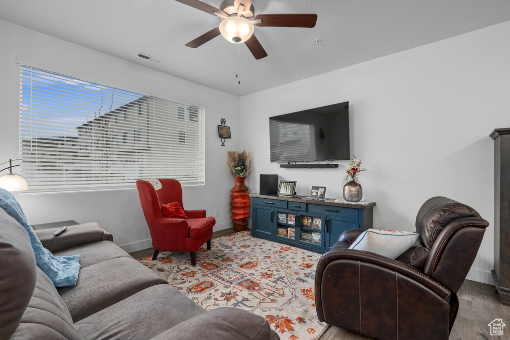 Living area with wood finished floors, visible vents, a ceiling fan, and baseboards