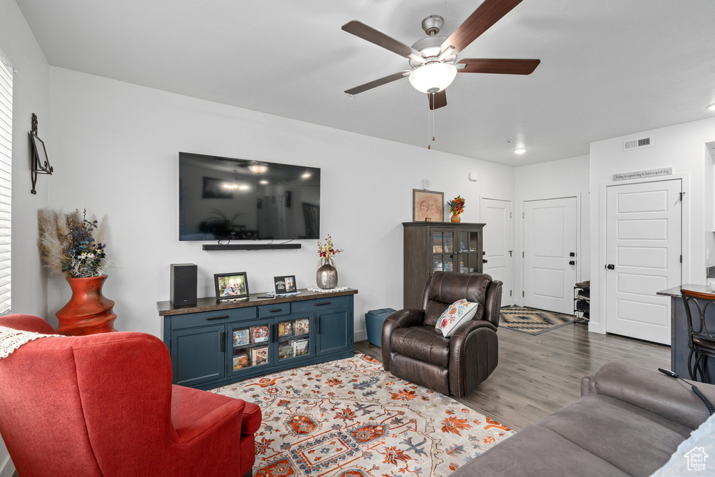 Living area with visible vents, a ceiling fan, and wood finished floors
